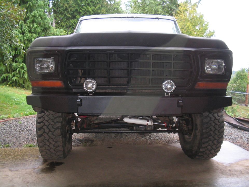 Front view of flat-black lifted Ford Bronco with custom steel bumper and round driving lights