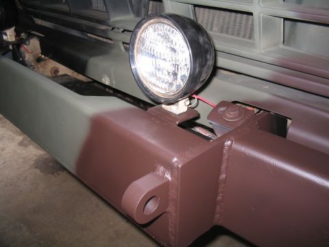 1979 Ford Bronco - Tight low-angle shot of a shop-built steel front bumper painted in green and brown camo, showing the welded box-tube center section, a thic…