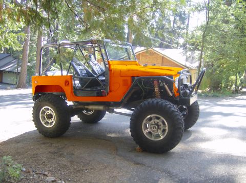 1989 Ford Bronco - This heavily modified off-road vehicle features a prominent roll cage and oversized tires, suggesting it is built for terrain.