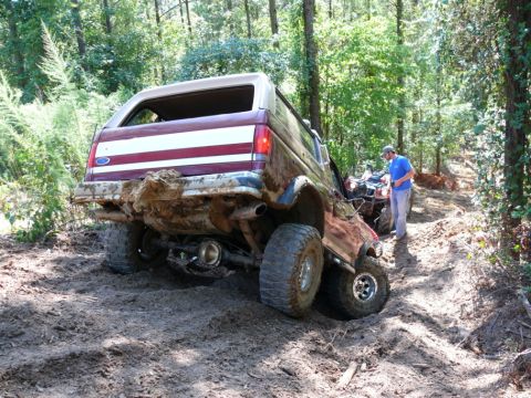 1988 Ford Bronco - A maroon and tan 1987 Ford Bronco is stuck in the mud on a wooded trail, with an ATV nearby.