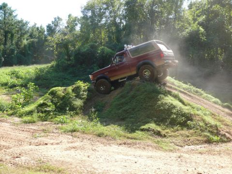 1988 Ford Bronco - A 1988 Ford Bronco navigates an off-road trail, kicking up dust.