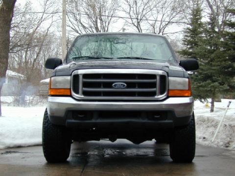 2000 Ford F-350 - Front view of a black Ford F-350 truck with a chrome grille and orange turn signals, parked on a wet surface in winter.