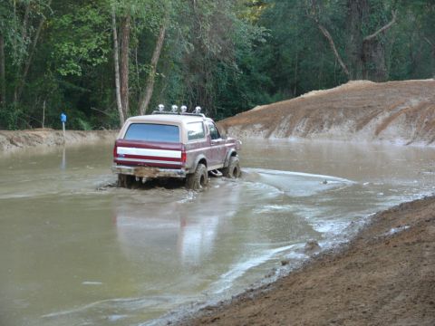 1988 Ford Bronco - Ford Bronco navigates a muddy water crossing in an off-road park.