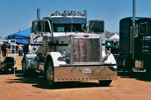 1981 Kenworth W900A - A white Peterbilt 379 semi-truck is parked outdoors, with another truck to its right.