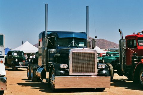 1981 Kenworth W900A - A blue semi-truck is parked at an outdoor event with other vehicles and tents in the background.