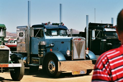 1981 Kenworth W900A - A blue Peterbilt 359 semi-truck is parked outdoors with other trucks visible.