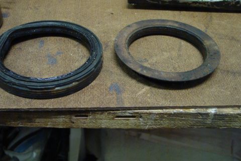 1993 Ford Bronco - A comparison of a new gasket next to a heavily rusted one, both resting on a wooden surface.