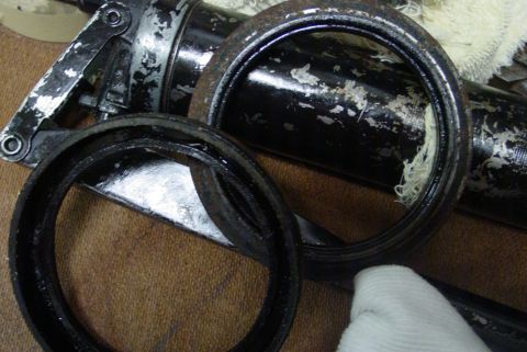 1993 Ford Bronco - Close-up of disassembled grease gun components and a grease gun on a textured surface.