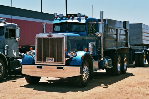 1981 Kenworth W900A - A blue dump truck is parked outdoors, with a portion of another truck visible to its left.