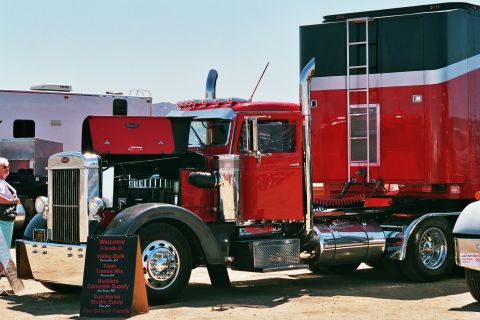 1981 Kenworth W900A - A classic red semi-truck and trailer are displayed, with a sponsor sign in the foreground.