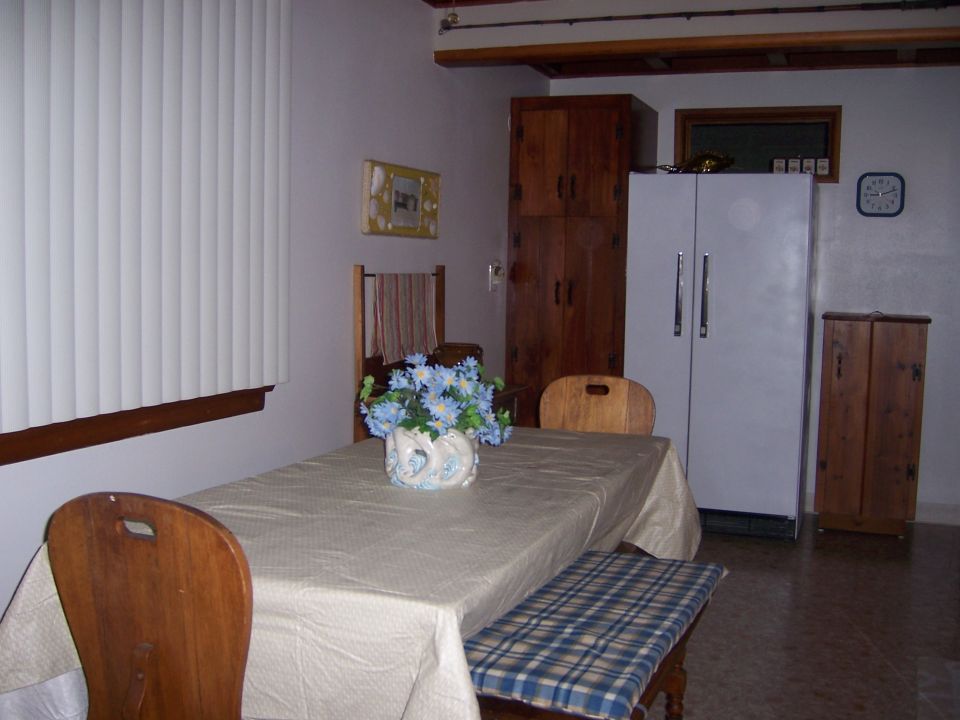 Interior scene with dining table, chairs, bench, refrigerator, and cabinets
