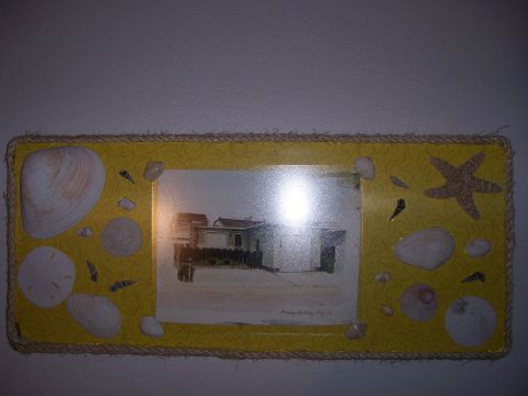 1991 Ford Bronco - A framed photo of a beach house is decorated with various seashells and a starfish.