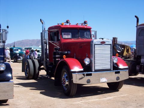 1981 Kenworth W900A - A red semi-truck cab is parked at an outdoor event with other vehicles visible.