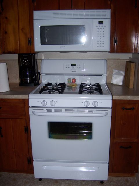1991 Ford Bronco - A white gas range and microwave are installed in a kitchen with wooden cabinets.