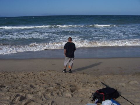 1991 Ford Bronco - Man fishing on the beach with waves crashing ashore.