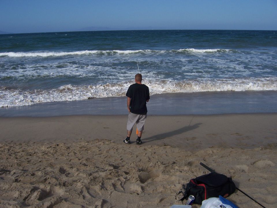 Man fishing in the ocean waves on a sandy beach