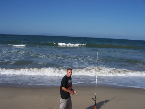 1991 Ford Bronco - A man stands on the beach with a fishing rod, ready to cast into the ocean waves.