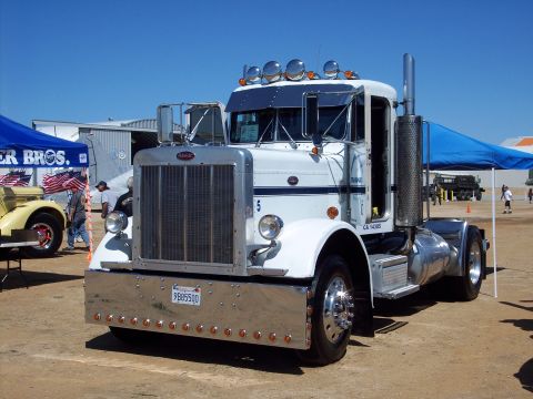 1981 Kenworth W900A - White Peterbilt 379 semi-truck at an outdoor event, with a yellow vehicle in the background.