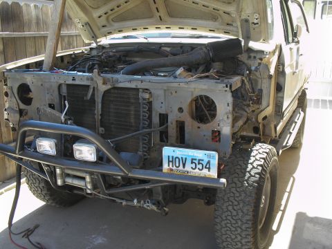 1990 Ford Bronco - This truck's front end is disassembled, revealing the engine and radiator components. It has a custom bumper with a winch and lights.