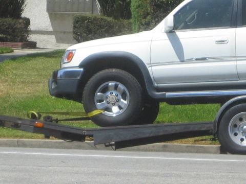 1968 Ford Mustang - A white SUV is secured to a trailer with yellow straps, viewed from the side.