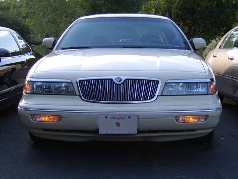 1996 Mercury Grand Marquis - Direct front view of a cream/beige Mercury Grand Marquis sedan with a chrome vertical-bar grille, Mercury emblem, dual headlights with ambe…