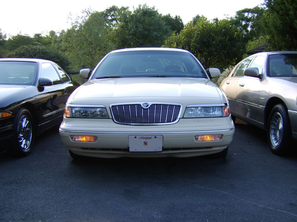 Cream Mercury Grand Marquis sedan, front view, Maryland plate, parked between two cars