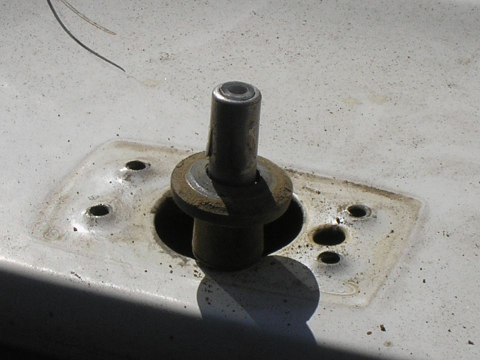 Close-up of a metal post protruding from a mounting plate with several bolt holes