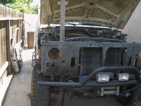 1990 Ford Bronco - This Ford Bronco is undergoing repairs or modifications, with its front end partially dismantled and the hood propped open.