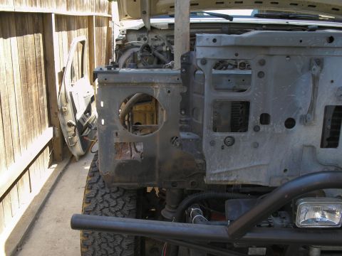 1990 Ford Bronco - The front end of a vehicle is disassembled, revealing engine components and the inner structure, with a detached door propped against a woo…