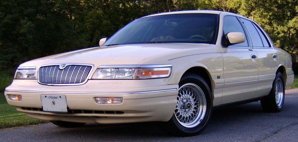 Beige Mercury Grand Marquis sedan, front 3/4 view, chrome grille and alloy wheels.