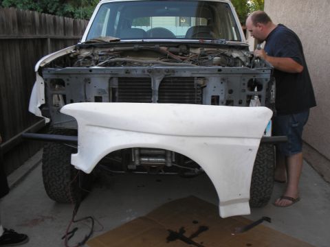 1990 Ford Bronco - Man works on the engine of a 1990 Ford Bronco, with a new fender ready to be installed.