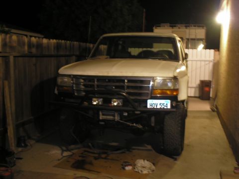 1990 Ford Bronco - This white SUV, likely a 1992 model, features a prominent aftermarket bumper and winch, with a visible license plate.