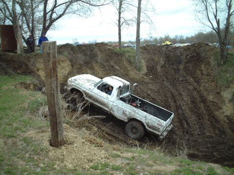 1979 Ford F-150 - A white 1979 Ford F-150 navigates a steep, muddy incline during an off-road event.