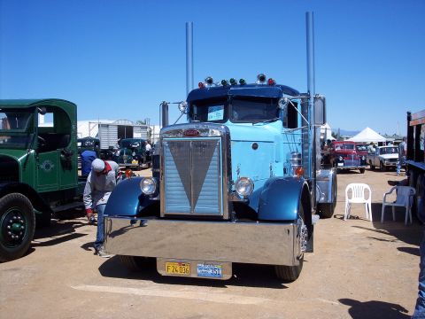 1981 Kenworth W900A - A blue semi-truck is parked outdoors with other vehicles and people around.