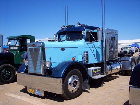 1981 Kenworth W900A - A blue semi-truck is parked at an outdoor event with other vehicles visible.