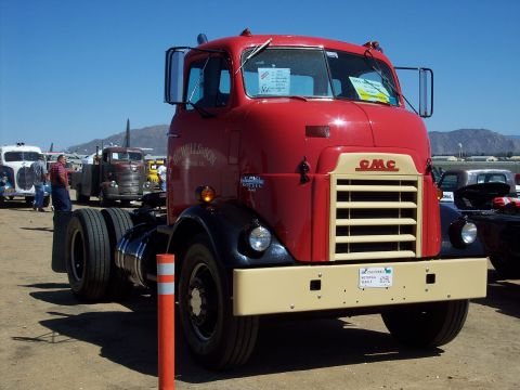 1981 Kenworth W900A - Front view of a red GMC truck at an outdoor event with other vehicles present.