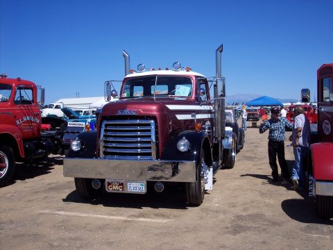 1981 Kenworth W900A - A classic GMC truck is displayed at an outdoor event with other vehicles and people.