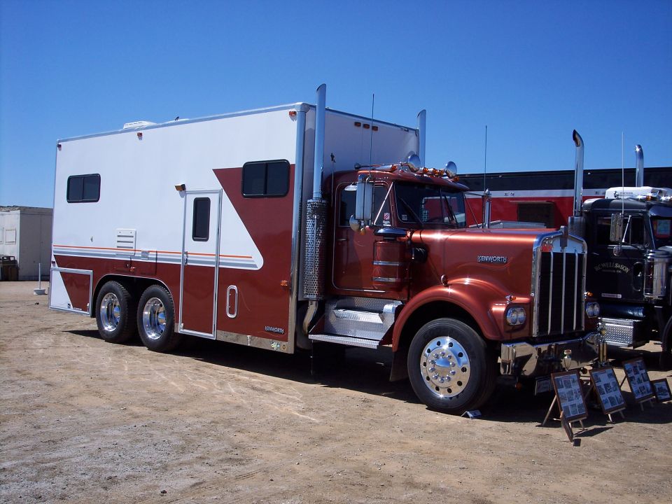 Copper and white Kenworth truck with box body on dirt lot, 3/4 front view