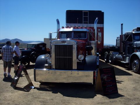 1981 Kenworth W900A - A classic Peterbilt truck is displayed at an outdoor event, alongside other vehicles and attendees.
