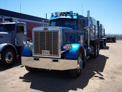 1981 Kenworth W900A - A blue semi-truck is parked next to another truck under a clear blue sky.