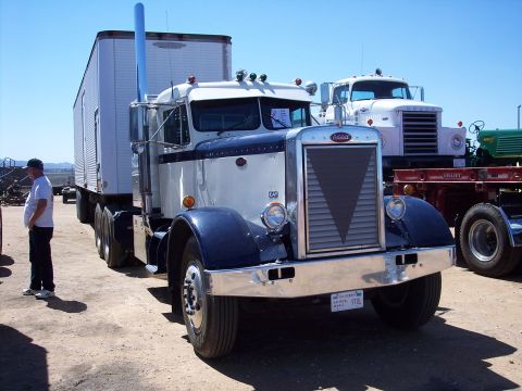 1981 Kenworth W900A - A classic white and blue semi-truck is parked outdoors, with another truck visible in the background.