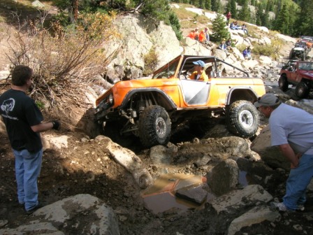 1995 Ford Bronco - An off-road vehicle navigates a challenging rocky trail with spectators present.