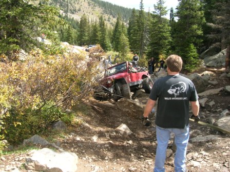 1995 Ford Bronco - Several off-road vehicles tackle a challenging mountain trail, with one vehicle prominently positioned on the incline.