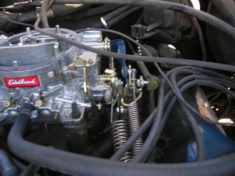 1978 Ford F-250 - Close-up view of an Edelbrock carburetor and associated engine components, including throttle linkage and springs.