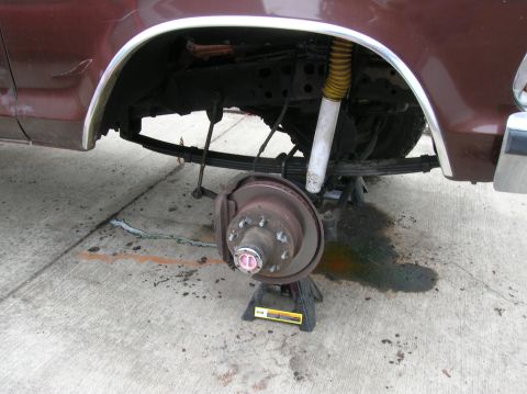 1978 Ford F-250 - The rear suspension of a vehicle is shown with the wheel removed and supported by jack stands.