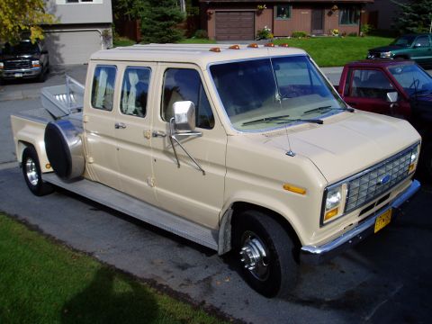 2000 Ford E350 - This extended cab pickup truck features a unique side-mounted spare tire and a long bed.