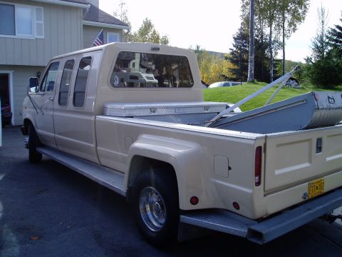 2000 Ford E350 - Tan extended cab pickup truck with a camper shell and a toolbox in the bed.