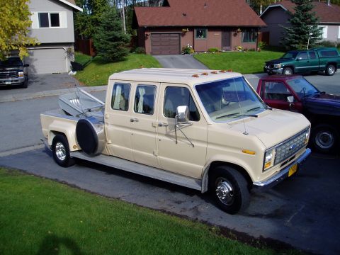 2000 Ford E350 - This custom van features an extended cab and a pickup truck bed, with a spare tire mounted externally.