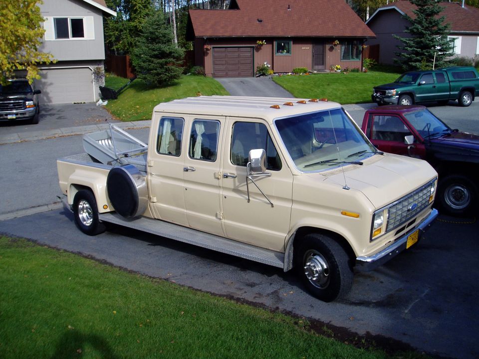 tan extended van with a truck bed and a spare tire mounted on the side, parked in a driveway