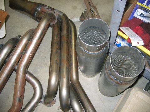 1992 Ford Mustang - Custom exhaust components, including headers and mufflers, are laid out on a workshop floor.
